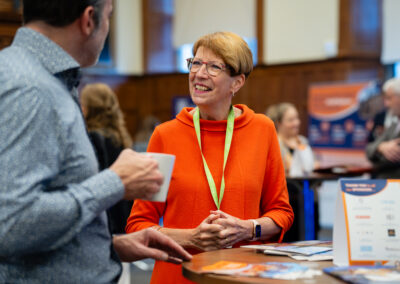 Image of individual smiling at business networking event while talking to another attendee
